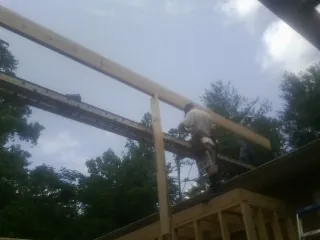 Carpenter setting a ridge beam over a new addition frame — Ice Dam Removal by Roofing Brothers in Purchase