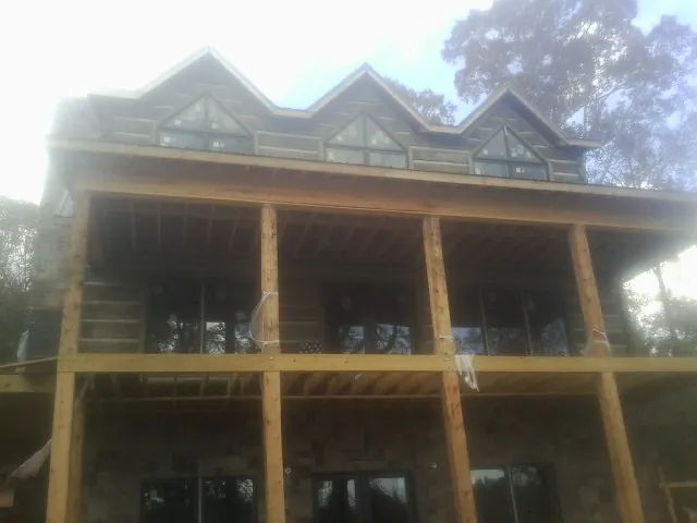 Dormers and porch framing on a large log home under construction — Roof Coating work by our crew in Purchase