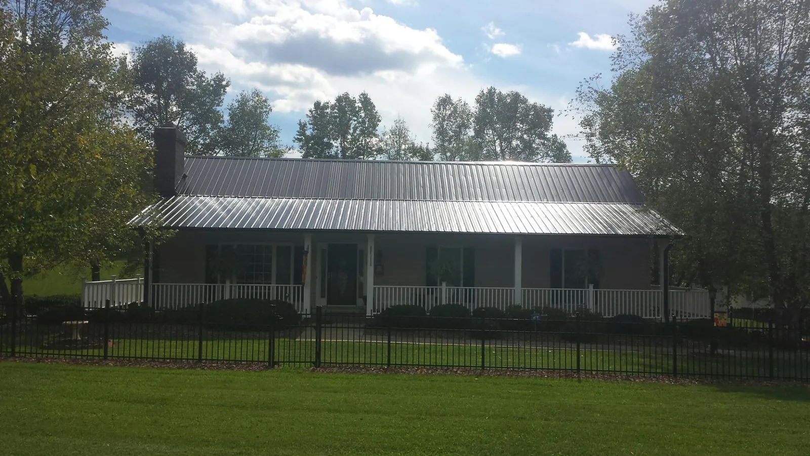 Gray metal roof on a brick ranch with a full width front porch — Gutter Guard Installation work by our crew in Purchase