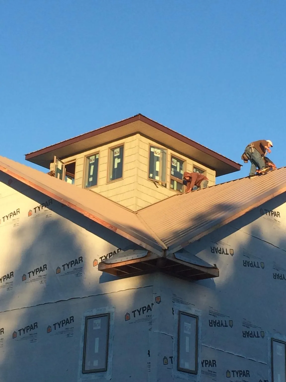 Roofers working around a rooftop cupola on a new metal roof at sunset — Roof Waterproofing in Purchase by Roofing Brothers